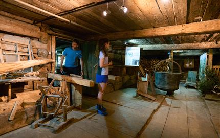 A traditional wooden building with rustic interior. Two people are in the room exploring the surroundings.