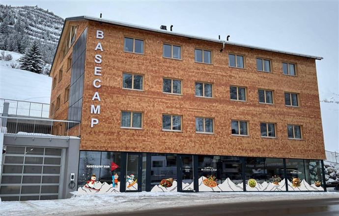 A modern building with the inscription "BASECAMP" in winter.  
Surrounded by snow and mountains.