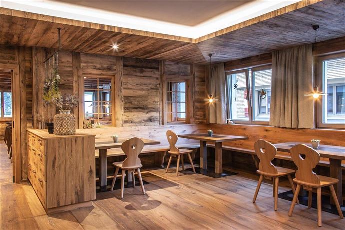 A cozy restaurant with wooden paneling and warm light. The furniture is simple and inviting, perfect for social gatherings.