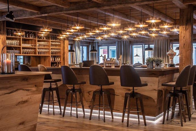 A modern bar interior with wooden details and stylish lighting. The seating is inviting and creates a cozy atmosphere.