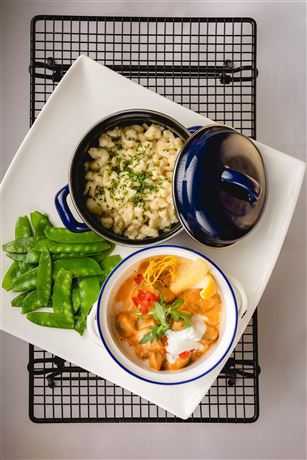 A dish with pasta, vegetables, and a creamy sauce. Served with cheese pasta and green beans.