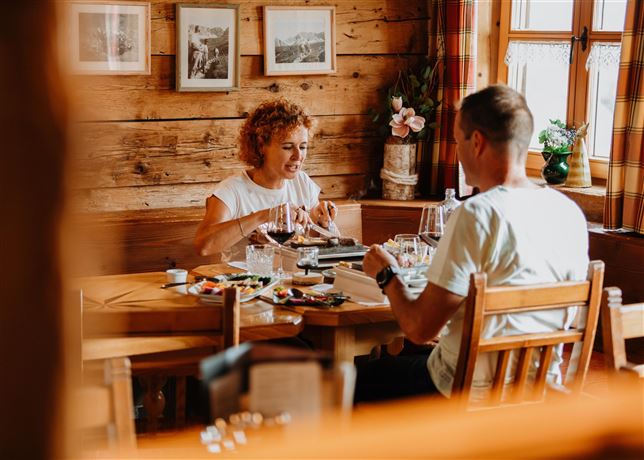A couple enjoys a delicious meal in a rustic restaurant. The cozy atmosphere is highlighted by wooden walls and loving decorations.