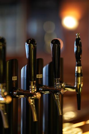 A row of taps in a bar. In the background, the atmosphere is subdued and cozy.