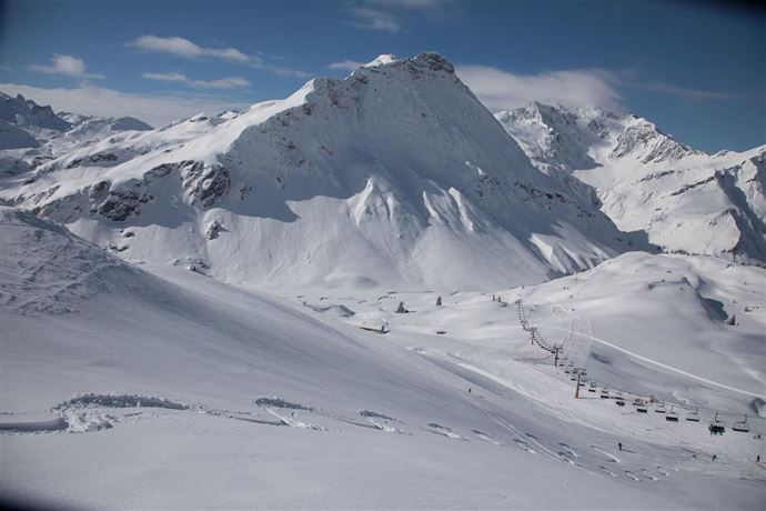 An impressive winter landscape with snow-covered mountains. Ski lifts wind their way through the untouched blanket of snow.