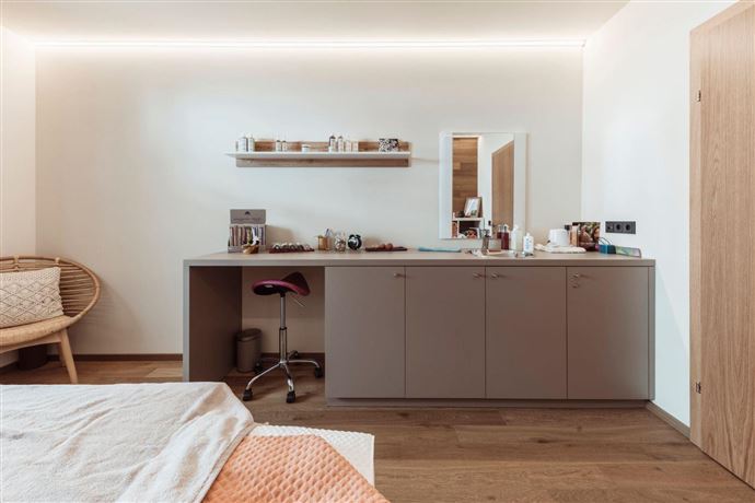 A modern room with warm wooden floors and minimalist decor. A small table with chairs and decorative elements creates an inviting atmosphere.