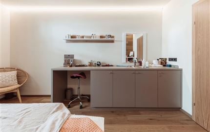 Ein modernes Zimmer mit warmen Holzböden und minimalistischer Einrichtung. Ein kleiner Tisch mit Stühlen und dekorativen Elementen schafft eine einladende Atmosphäre.