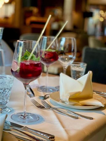 An elegant table with drinks and beautifully folded napkins. The glasses are filled with a refreshing red-colored cocktail.