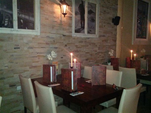 Ein gemütliches Restaurant mit Holztischen und eleganten Stühlen. Sanfte Beleuchtung durch Kerzen und Wandleuchten schafft eine warme Atmosphäre.