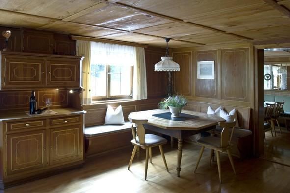 A cozy dining area with wooden paneling and a round table. A window provides natural light and an inviting atmosphere.