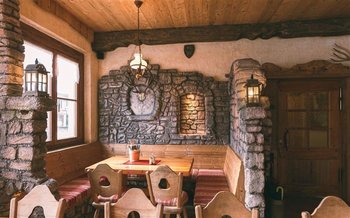 A cozy restaurant with wooden furniture and a stone wall. The warm lights create an inviting atmosphere.