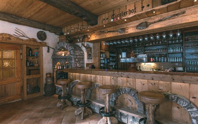 A cozy wooden bar with bar stools and an expansive counter. The warm colors and rustic details create an inviting atmosphere.