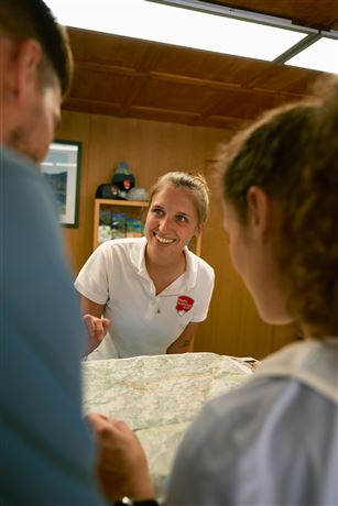 A friendly employee explains something about a map. Two people listen attentively and look at the map.