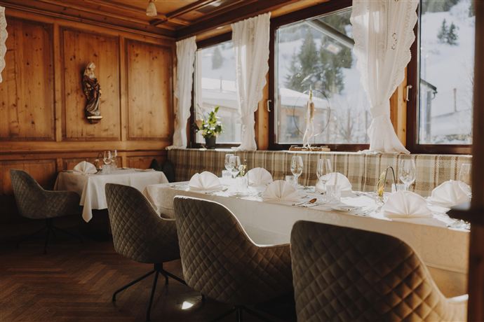 A cozy restaurant with wooden paneling and large windows. The tables are elegantly set and invite relaxation.