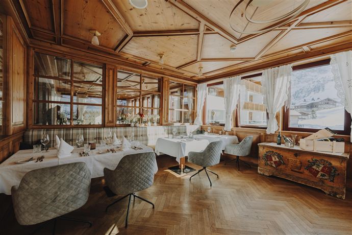 A cozy restaurant with wooden details and large windows. The tables are elegantly set and invite you to linger.