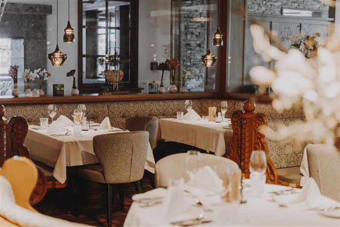 An elegant restaurant with beautifully set tablecloths and subdued lighting. The decor is modern and inviting.