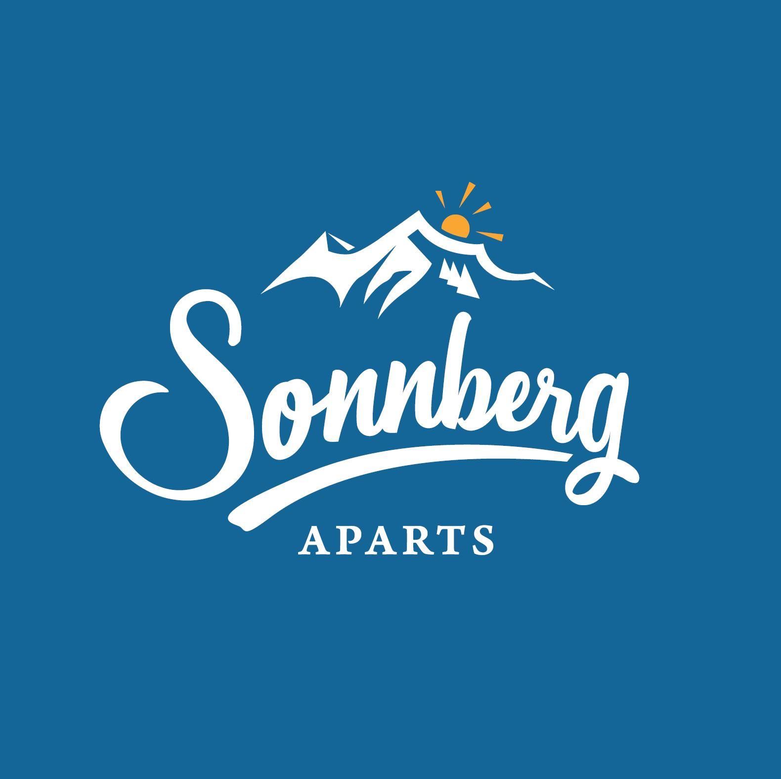 A logo of Sonmberg Aparts featuring a mountain landscape and a sun. The background is blue and the lettering is in white.