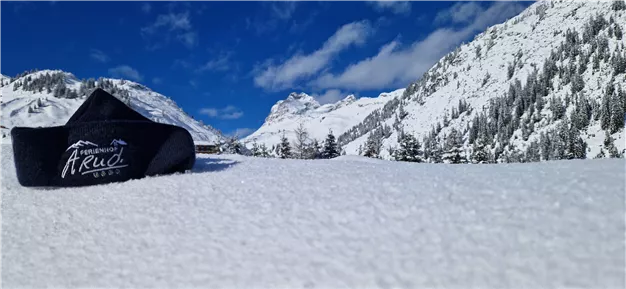 A snow-covered area with impressive mountains in the background. The clear blue sky and clouds give the winter landscape a beautiful contrast.
