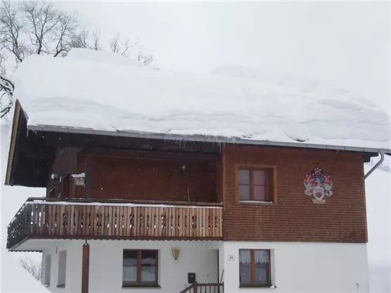 A cozy house in the snow with a snow-covered roof. The surroundings show winter landscapes.