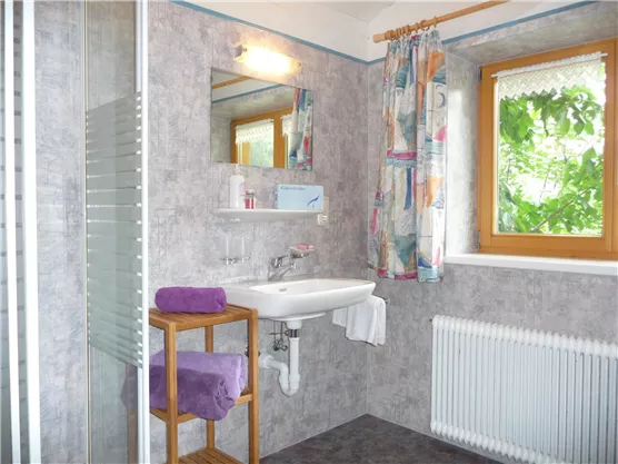 A modern bathroom with a shower, sink, and a large window.  
Colorful curtains and towels create an inviting atmosphere.