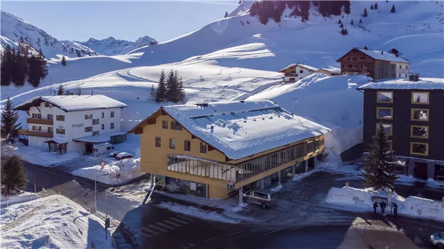 A picturesque winter landscape with snow-covered mountains. In the foreground, several houses create a cozy atmosphere.