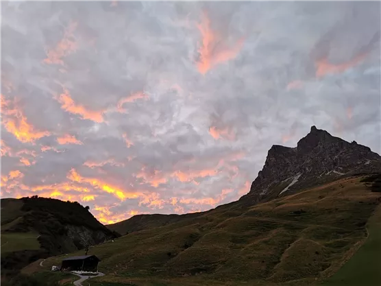 An impressive mountain at sunset, surrounded by gentle hills. The sky is painted in brilliant colors.