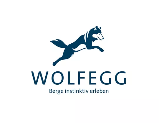 The logo of Wolfegg features a leaping wolf in blue color. Below it is the slogan "Experience the mountains instinctively."