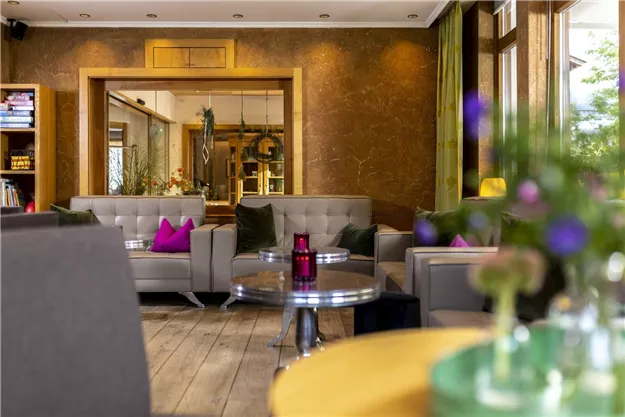 A modern café with comfortable seating and bright colors. In the background, another room is reflected, creating an inviting atmosphere.