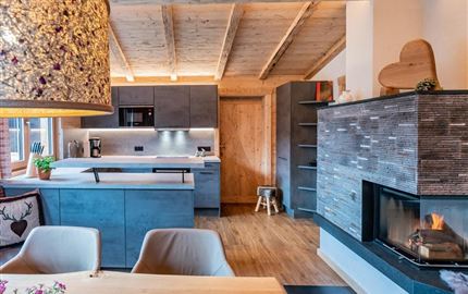 Modern kitchen with wooden details and an open living area. A cozy atmosphere with a fireplace and plenty of natural light.