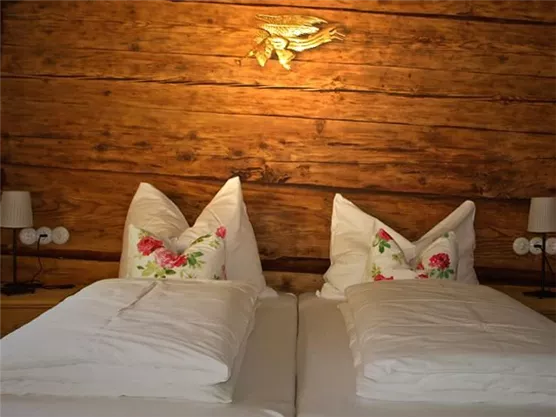 Ein gemütliches Schlafzimmer mit einem Doppelbett und dekorativen Kopfkissen. Die Wände sind aus Holz und verleihen dem Raum eine warme Atmosphäre.
